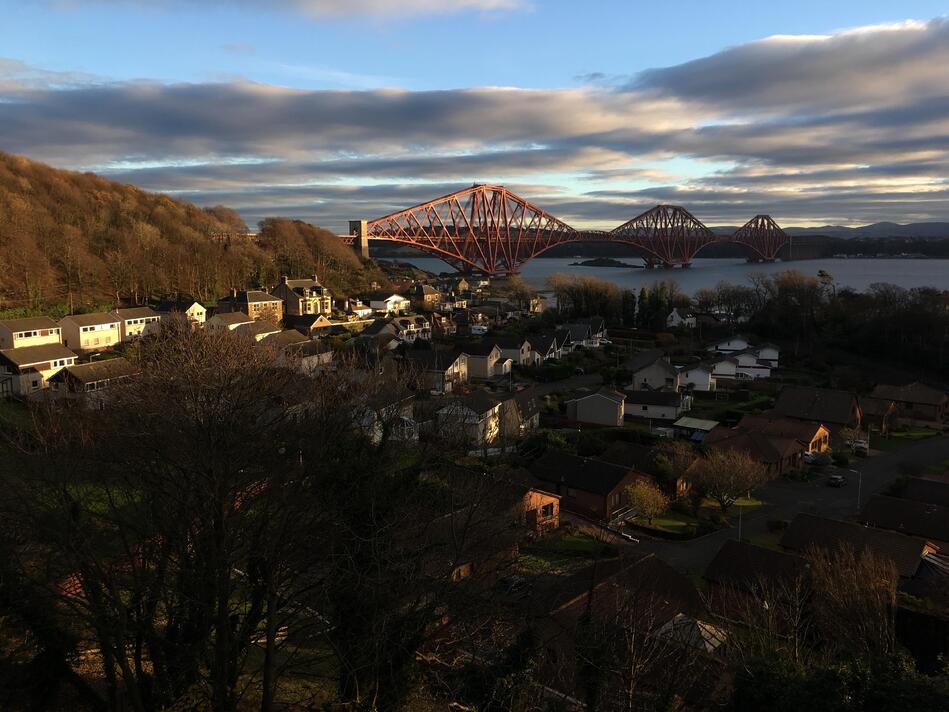 A village of houses in shadow in the foreground, with the bridge clearly visible in the background.